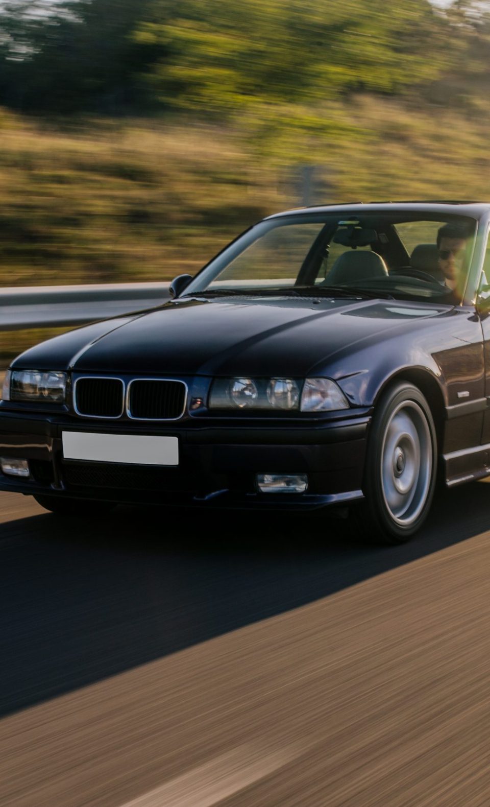 vintage-sedan-car-driving-sunlight-road